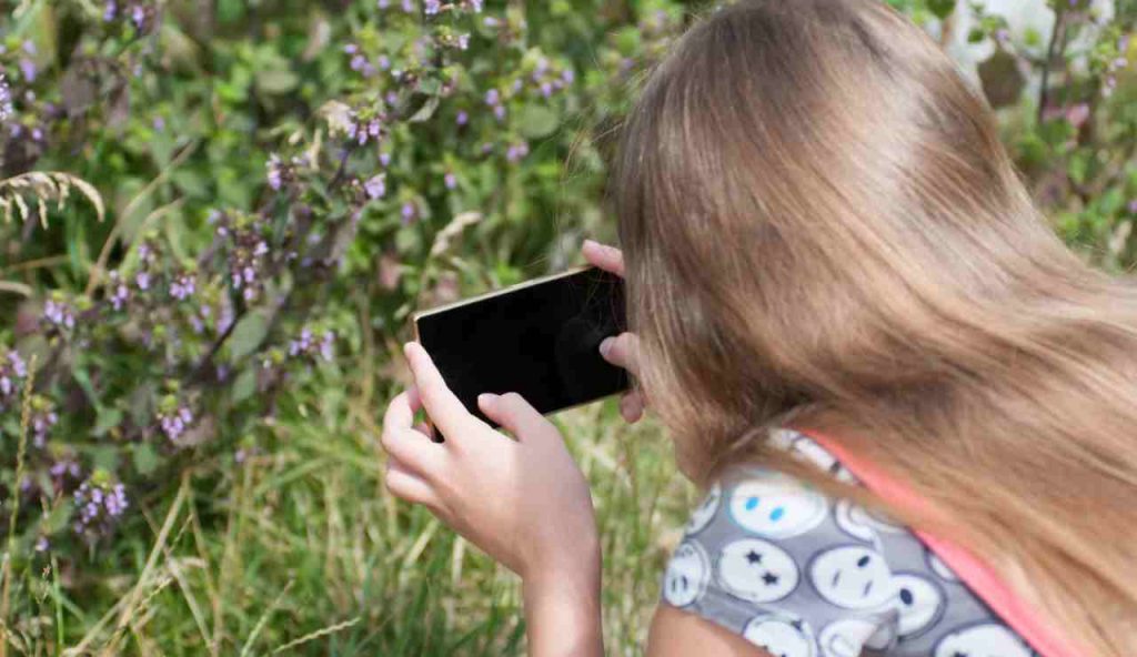 Donna punta una pianta con uno smartphone