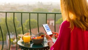 Donna seduta in un balcone con uno smartphone in mano con dei messaggi