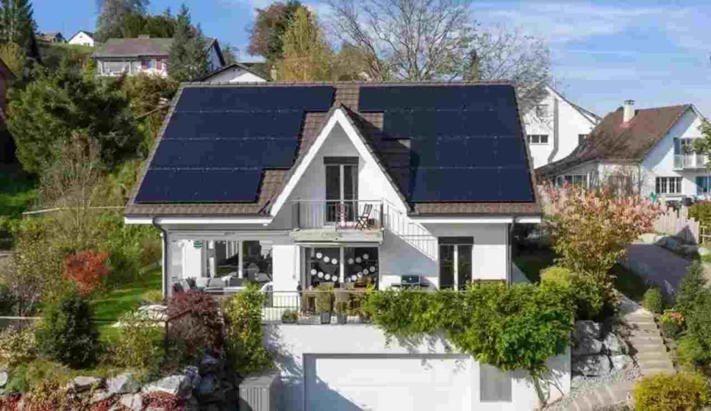 Casa con dei pannelli fotovoltaici sul tetto immersa nel verde