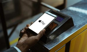 Mano di persona che paga con un iPhone con il servizio Apple Pay attivo