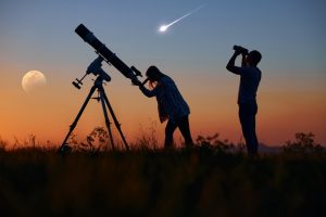 Uomo e donna osservano il cielo con un telescopio e un cannocchiale