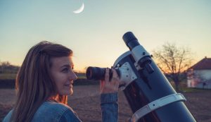 Donna osserva il cielo con il telescopio